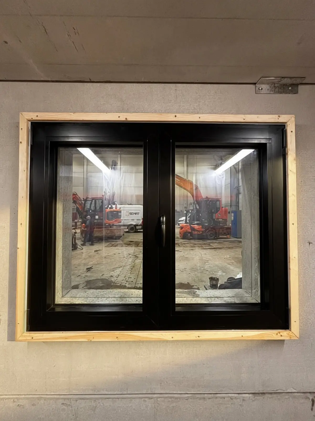 Châssis aluminium noir à deux ouvrants posé par Arena Invest dans une ouverture encadrée de bois